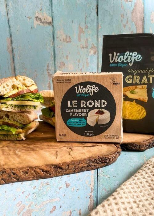 Violife Cheese Review From A Non-Vegan 2 two packs of violife cheese review on a wooden board, beside a cheese sandwich, all on a wooden board, blue background