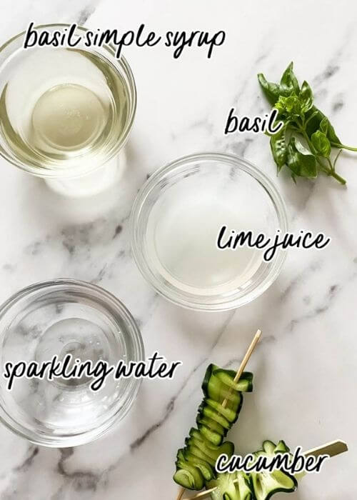 cucumber basil mocktail ingredients in bowls on a marble background