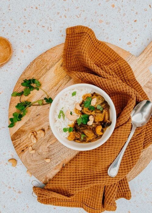 Vegan Mushroom Korma, The #1 Best Recipe 2 mushroom korma in a bowl, a napkin, wooden board and spoon, parsley on the side, above