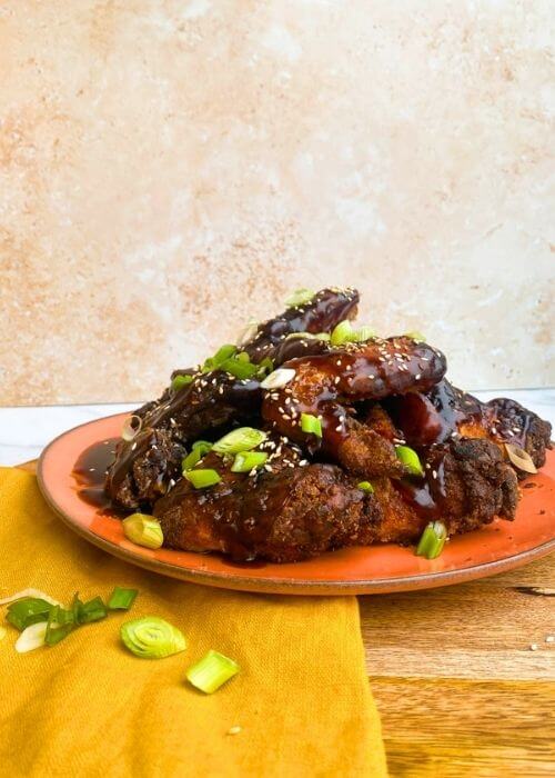 Best Crispy Fried Soy Garlic Chicken Wings Recipe 4 soy garlic chicken wings on a plate, on a wooden board and yellow towel