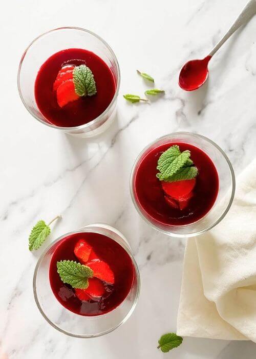 The Best Vegan Panna Cotta 2 from top vegan panna cotta in glasses on a marble background, a spoon and mint leaves on the side, towel on the side