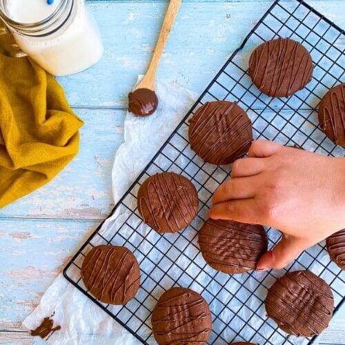 hand reaching for a nutella cookies, cookies on a rack, parchment paper under