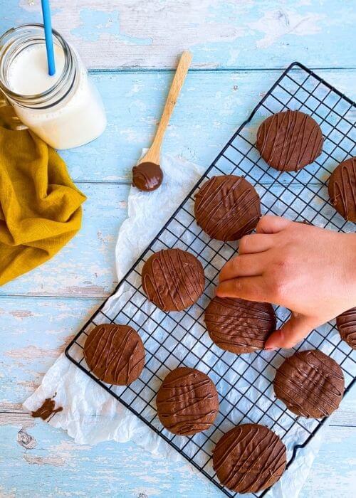hand reaching for a nutella cookies, cookies on a rack, parchment paper under