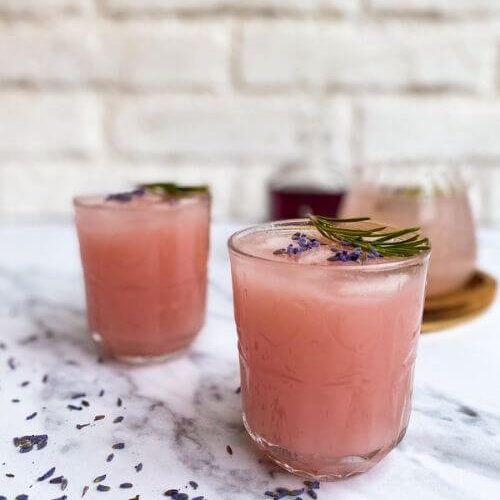 Lavender Lemonade Cocktail 20 Minutes Delicious Drink 6 lavender lemonade cocktail in glasses, more cocktail mix, a bottle of lavender syrup, marble table