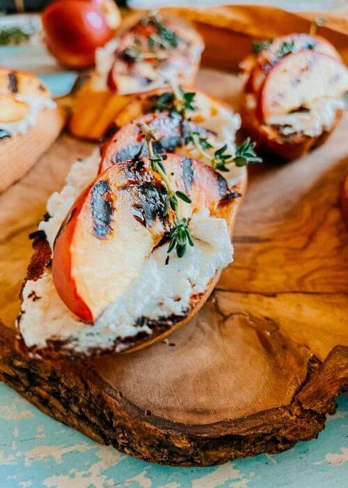 Delicious Peach Ricotta Crostini with Thyme and Balsamic 4 detail - peach and ricotta crostini on a wooden board, more ricotta on the background
