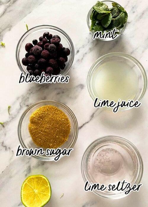 Delicious Blueberry Mojito Mocktail Recipe 2 blueberry mojito mocktail ingredients in bowls on a marble background