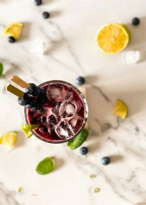Delicious Blueberry Mojito Mocktail Recipe 4 2.blueberry mojito mocktail from top with ingredients around on marbled background