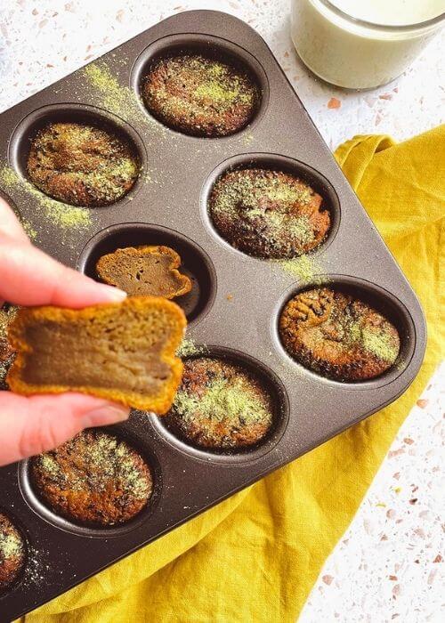 Delicious Matcha Mochi Muffins 1 matcha mochi muffins in a tin on a yellow napkin, a hand squeezing a muffin, pin image